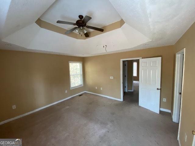 unfurnished bedroom featuring baseboards, a raised ceiling, and carpet floors