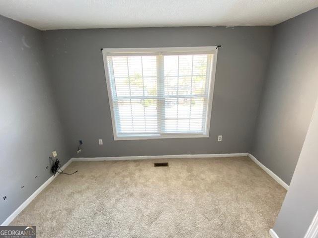 carpeted empty room featuring visible vents and baseboards