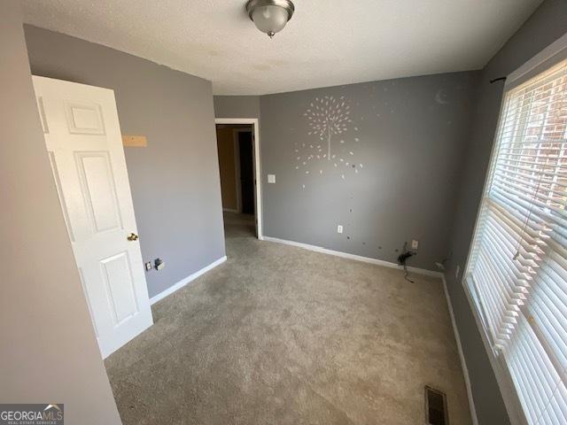carpeted spare room featuring visible vents and baseboards