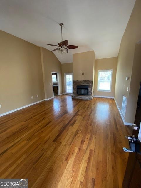 unfurnished living room featuring light wood-type flooring, a wealth of natural light, ceiling fan, and vaulted ceiling
