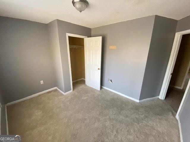 unfurnished bedroom with baseboards, carpet floors, and a closet