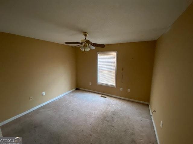 empty room with baseboards, visible vents, ceiling fan, and carpet flooring