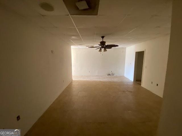 spare room with a ceiling fan, concrete floors, and a drop ceiling