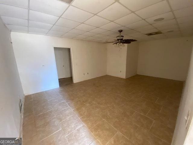 empty room featuring ceiling fan and a drop ceiling