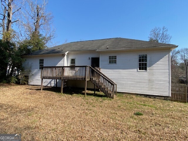 rear view of house with fence, stairway, a deck, and a yard