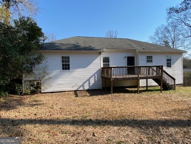 back of house featuring a lawn and a deck