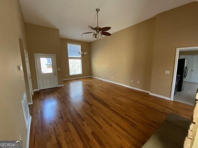 unfurnished living room featuring wood finished floors, ceiling fan, vaulted ceiling, and baseboards