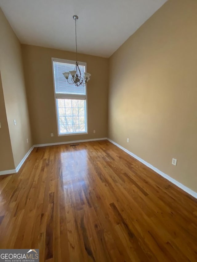 interior space featuring baseboards, wood finished floors, and an inviting chandelier
