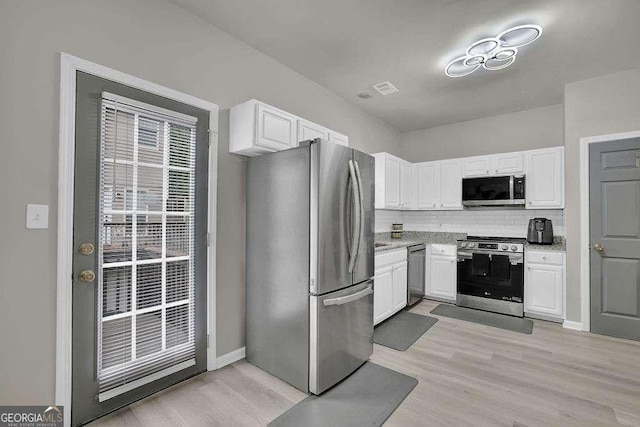 kitchen featuring stainless steel appliances, light wood-type flooring, white cabinets, and backsplash