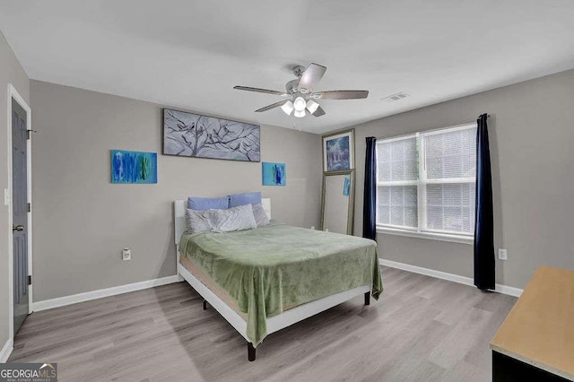 bedroom with light wood finished floors, a ceiling fan, visible vents, and baseboards