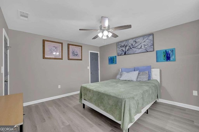 bedroom featuring baseboards, visible vents, a ceiling fan, and light wood-style flooring