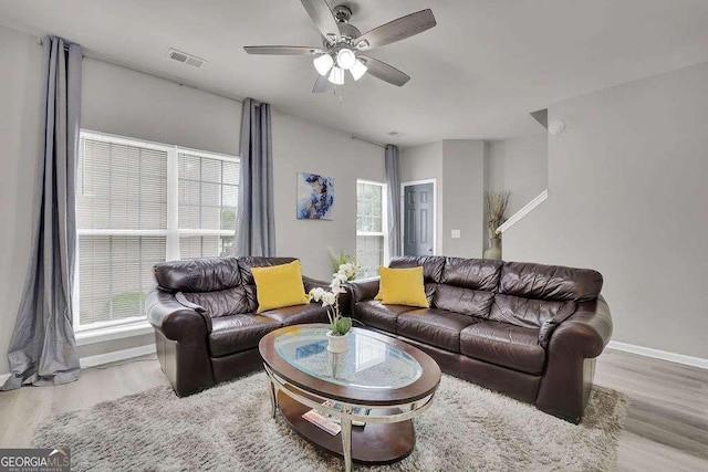 living room featuring wood finished floors, a ceiling fan, visible vents, and baseboards