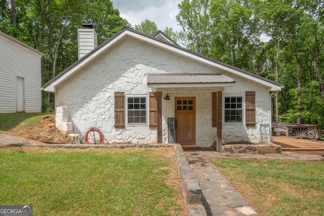 bungalow-style home featuring a front yard, stone siding, and a chimney