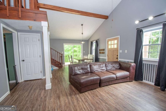 living room with beamed ceiling, stairs, a wealth of natural light, and wood finished floors