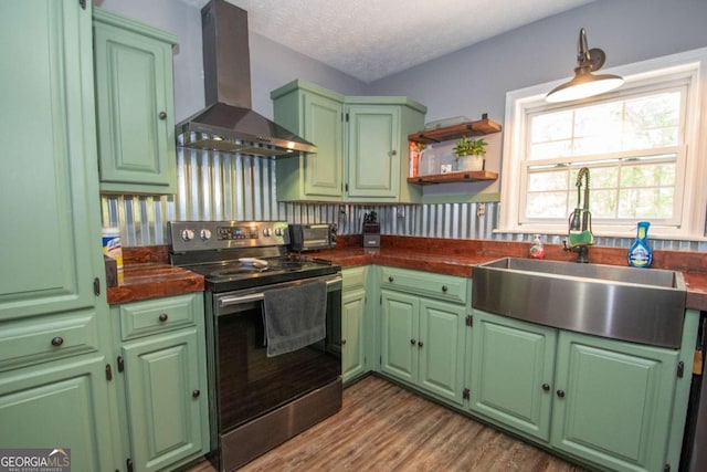 kitchen with wall chimney range hood, dark countertops, stainless steel range with electric stovetop, and a sink