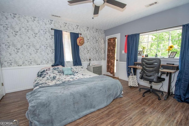 bedroom featuring a wainscoted wall, visible vents, and multiple windows