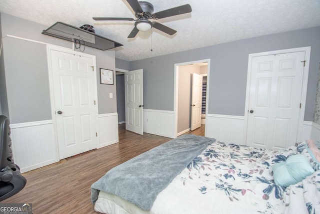 bedroom with wainscoting, wood finished floors, ceiling fan, and a textured ceiling