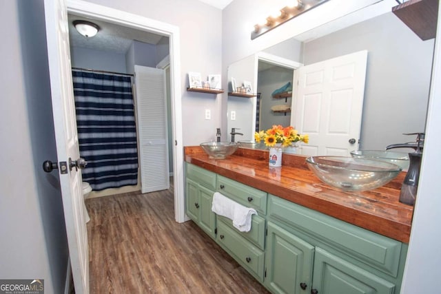 bathroom with double vanity, wood finished floors, and a sink