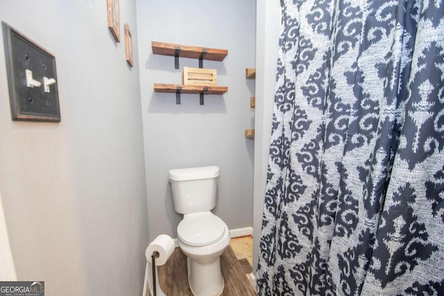 full bath with wood finished floors, curtained shower, toilet, and baseboards