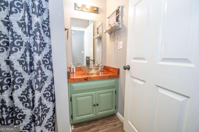 full bath with a shower with curtain, vanity, and wood finished floors