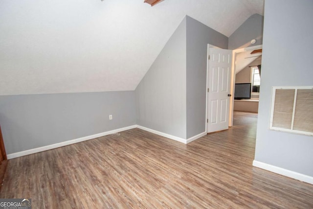 bonus room featuring lofted ceiling, wood finished floors, visible vents, and baseboards