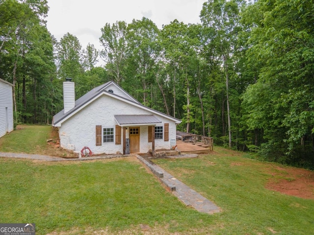 bungalow-style home with a front yard, a deck, stone siding, and a chimney