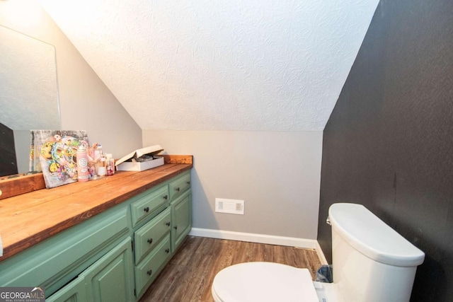 bathroom with vanity, toilet, visible vents, a textured ceiling, and wood finished floors