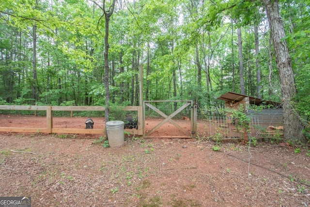 view of gate featuring a forest view and fence