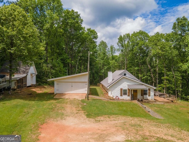 view of front facade featuring driveway, an outdoor structure, a chimney, a front yard, and a garage