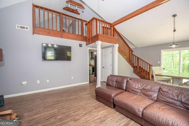 living area featuring wood finished floors, stairs, baseboards, visible vents, and high vaulted ceiling