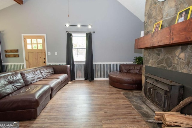 living area featuring wood finished floors, beamed ceiling, high vaulted ceiling, and a wood stove