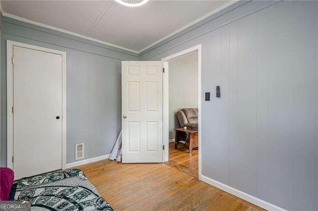 bedroom featuring crown molding, visible vents, wood finished floors, and baseboards