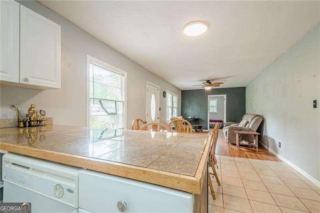 kitchen with a peninsula, white dishwasher, white cabinetry, a ceiling fan, and open floor plan