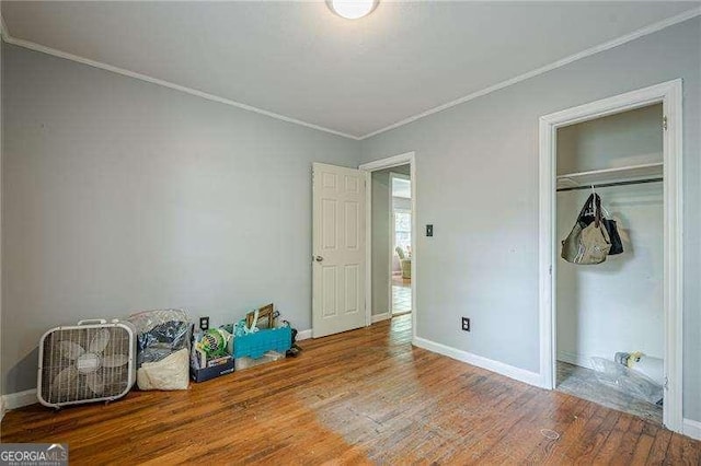 unfurnished bedroom featuring baseboards, wood finished floors, and crown molding