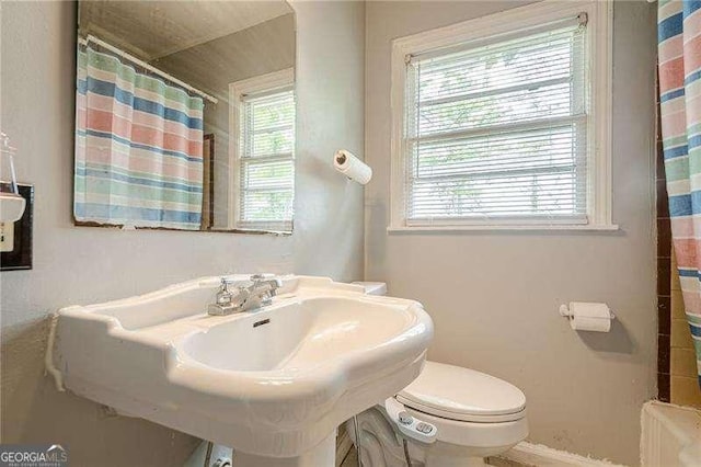 bathroom with toilet, a shower with curtain, and baseboards