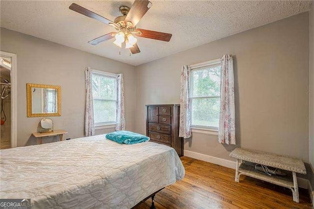 bedroom with wood finished floors, baseboards, a ceiling fan, and multiple windows