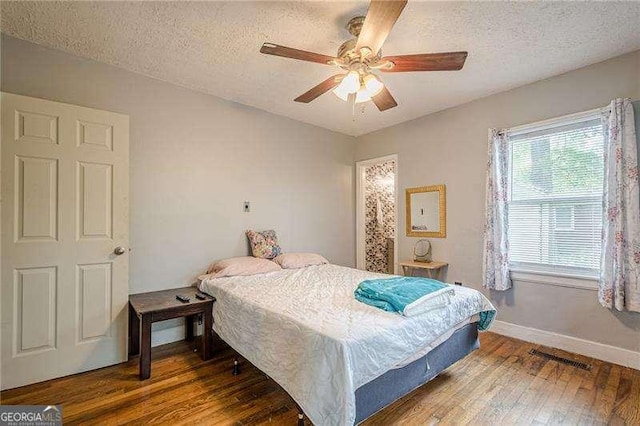 bedroom featuring a textured ceiling, hardwood / wood-style floors, and baseboards
