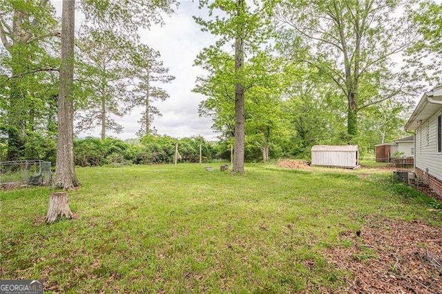 view of yard featuring an outbuilding, a storage shed, and fence