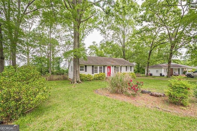 ranch-style home featuring fence and a front lawn