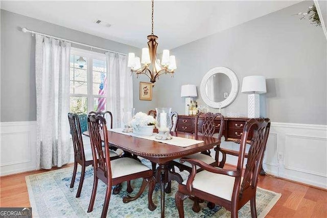 233 Hampton Station Blvd, Canton, GA 30115 - dining space with light wood-style floors, a decorative wall, wainscoting, and a chandelier