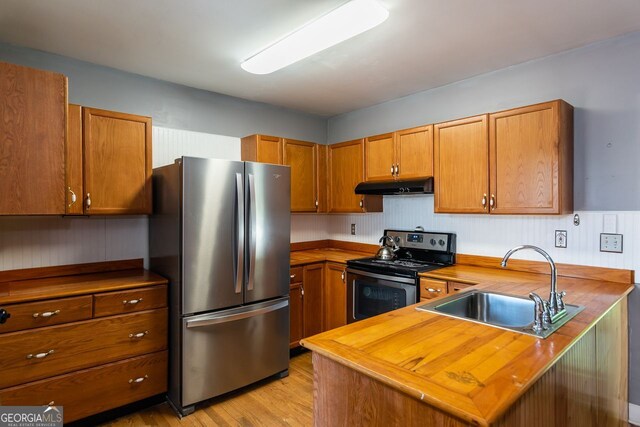kitchen featuring stainless steel appliances, under cabinet range hood, a sink, wooden counters, and brown cabinetry