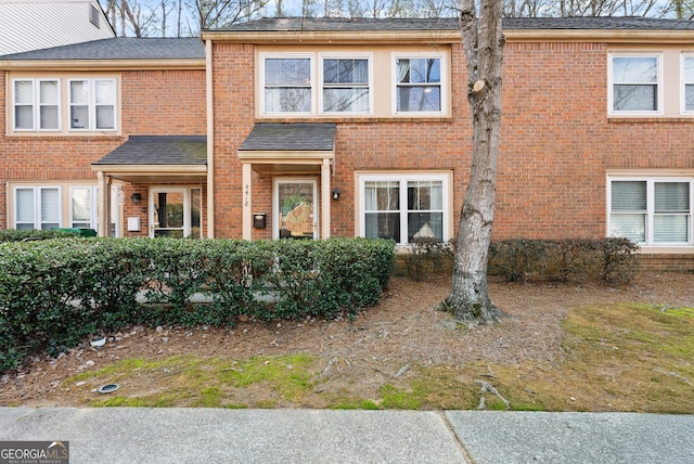 view of property with brick siding and roof with shingles