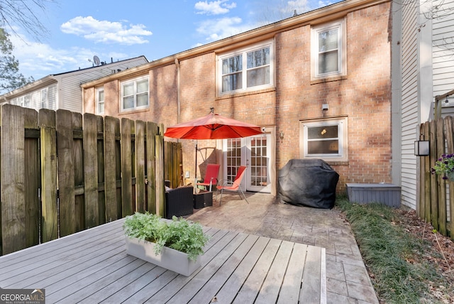 rear view of property with fence, a patio area, a deck, and brick siding