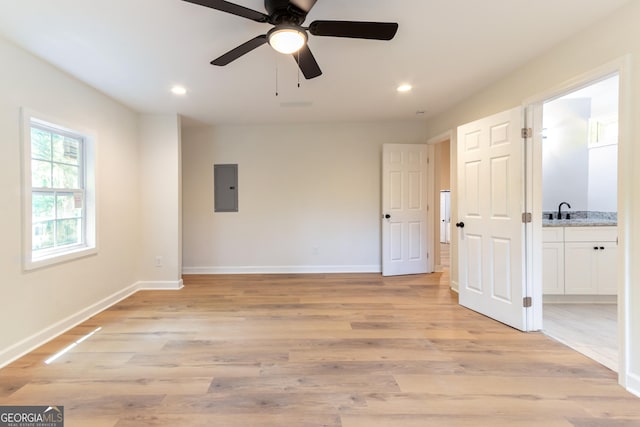 spare room with light wood finished floors, recessed lighting, electric panel, and baseboards