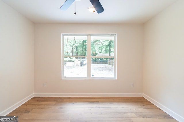 spare room featuring ceiling fan, baseboards, and light wood-style floors