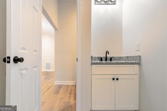 bathroom featuring wood finished floors, vanity, visible vents, and baseboards