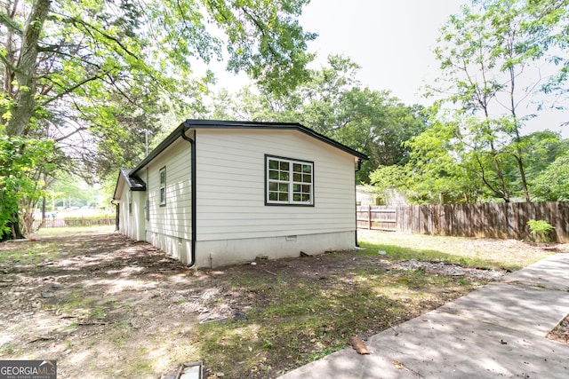 view of side of home with fence and crawl space