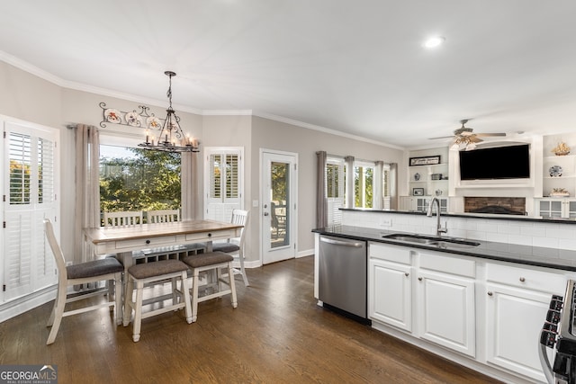 kitchen with dark countertops, a sink, appliances with stainless steel finishes, and ceiling fan with notable chandelier