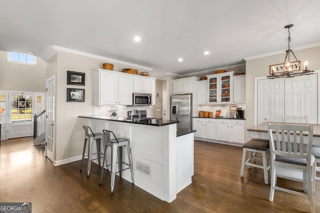 kitchen featuring a chandelier, stainless steel appliances, crown molding, and white cabinetry