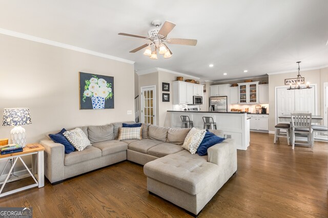 living area featuring recessed lighting, ornamental molding, ceiling fan with notable chandelier, and dark wood-type flooring